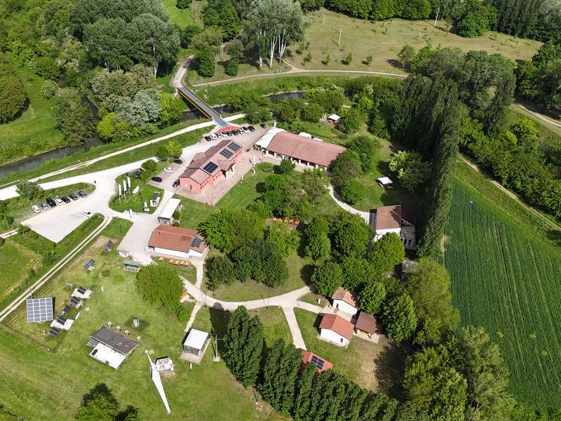 Il Fenice Green Energy Park visto dall'alto: edifici con pannelli solari, prati, viali e alberi lungo il canale.